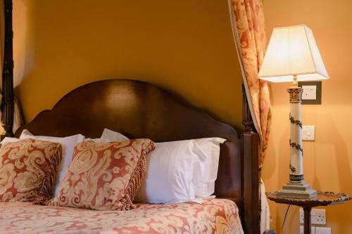 a bed with a black headboard and a lamp at The Crown, Bildeston in Bildeston