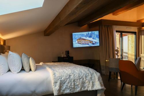 a bedroom with a bed with a tv on the wall at Domaine de Montagne - Hôtel Chalet Frère Joseph in Ventron