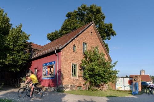 a person riding a bike in front of a brick building at Basiskulturfabrik Öko-Hotel in Neustrelitz