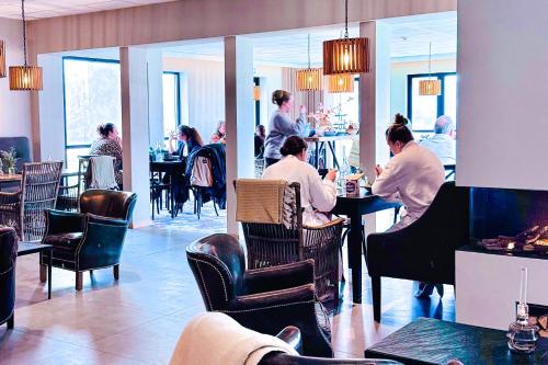 a group of people sitting at tables in a restaurant at Hotell Mossbylund in Abbekås