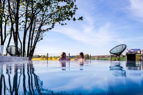 two people in a pool of water with chairs at Hotell Mossbylund in Abbekås