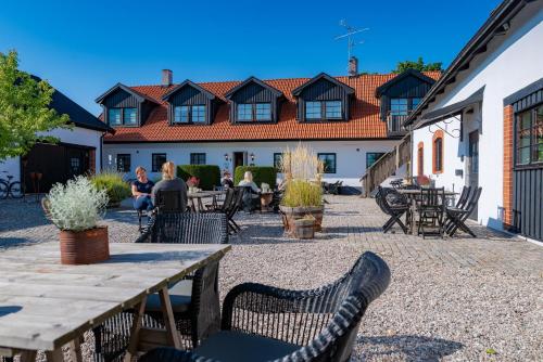 a patio with a table and chairs and a building at Hotell Mossbylund in Abbekås