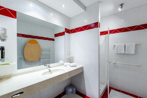 a red and white bathroom with a sink and a shower at Hotel Xylophon - inklusive Thermeneintritte in Lutzmannsburg