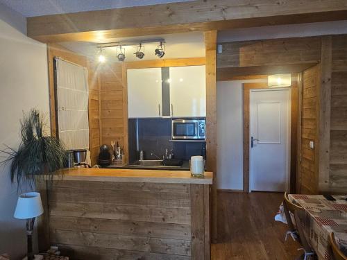 - une cuisine avec des murs en bois et un comptoir avec un évier dans l'établissement Appartement 2 pièces au milieu des chalets. Grande Terrasse Orientée Sud, à Saint-Étienne-de-Tinée
