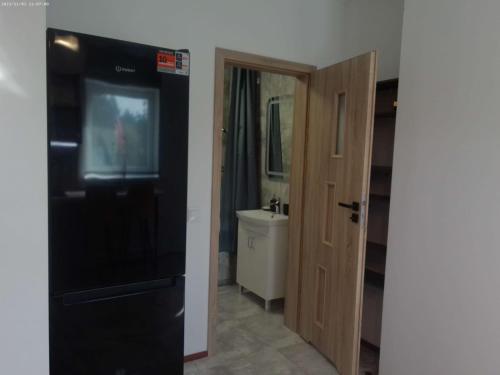 a bathroom with a black refrigerator and a sink at Vista premium apart in Choszczówka