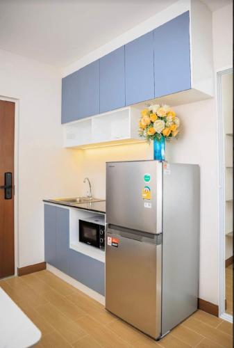 a kitchen with a refrigerator and a vase of flowers at Raspberry Mansion ราสเบอรี่ แมนชั่น in Samutprakarn