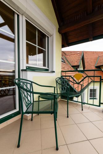 two green chairs on a balcony with a window at Hotel Xylophon - inklusive Thermeneintritte in Lutzmannsburg