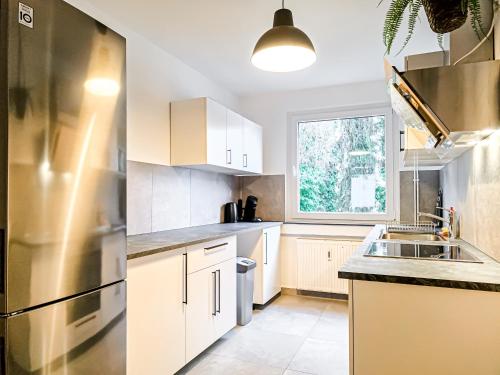 a kitchen with white cabinets and a stainless steel refrigerator at Centerline Apartments Solingen in Solingen