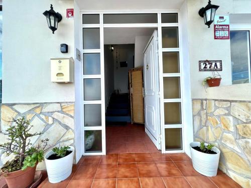 una porta che conduce a un corridoio con piante in vaso di Apartamentos Trebol a Mocanal