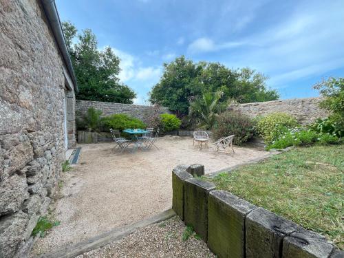 a garden with a stone wall and a table and chairs at Maison double en pierres pour grande famille ou groupe amis in Sibiril