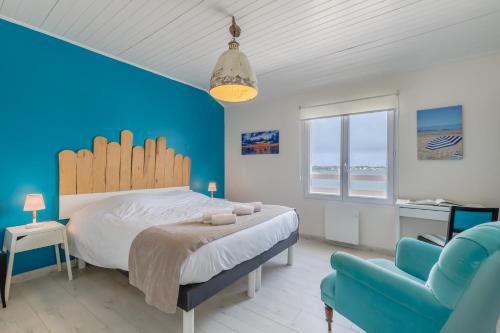 Un dormitorio con una cama grande y una pared azul. en Les Bains de Mer Vendee, en La Barre-de-Monts