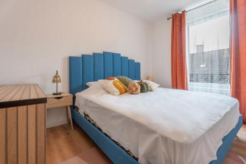 - un lit avec tête de lit bleue dans une chambre avec fenêtre dans l'établissement Centre Parking gratuit Bars restaurants, à Mulhouse