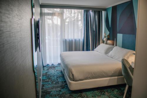 a bedroom with a bed and a window at Juliana Hotel Cannes in Cannes