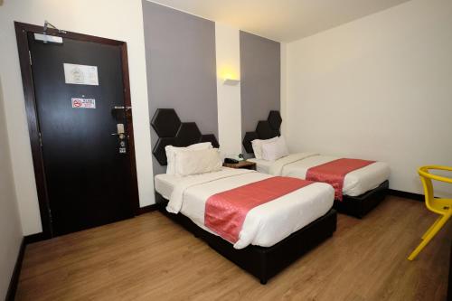 a hotel room with two beds and a door at Memoire Hornbill Hotel Kuching Sarawak in Kuching