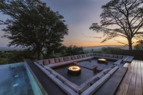 a pool with a fire pit with a sunset in the background at Serengeti Explorer in Serengeti
