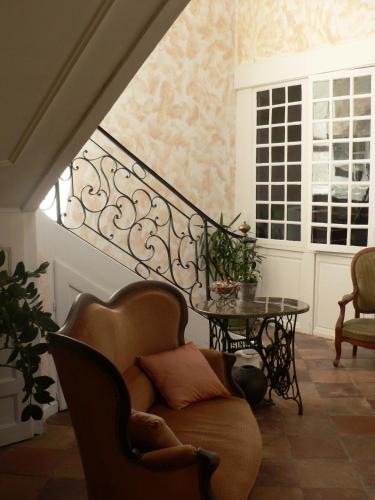 a room with a staircase with a chair and a table at La Terrasse de la Grand'Rue - chambre d'hôtes - in Mugron