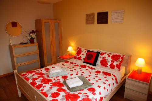 une chambre avec un lit avec des fleurs rouges dessus dans l'établissement Les Gîtes Champêtres Walnut cottage, à Sainteny
