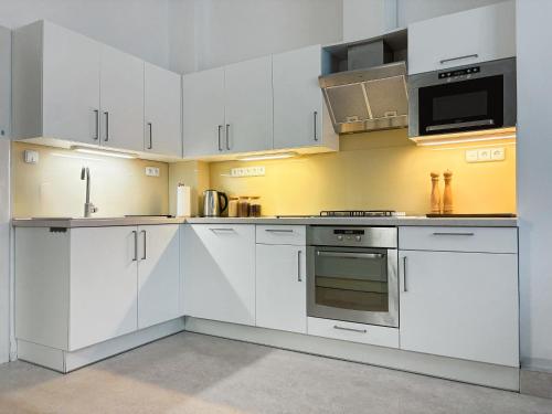 a kitchen with white cabinets and a stove top oven at Jako doma - centrally located apartment in Liberec
