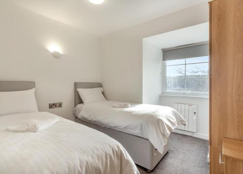 a bedroom with two beds and a window at Apartment with Access to Pool Spa & Soft play in Ilfracombe