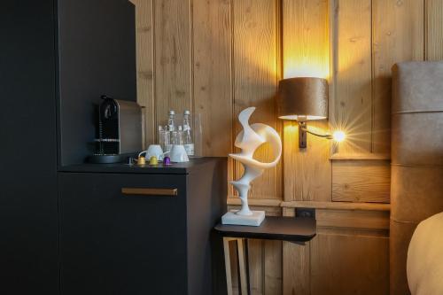a room with a bed with a lamp on a table at Domaine de Montagne - Hôtel Chalet Frère Joseph in Ventron