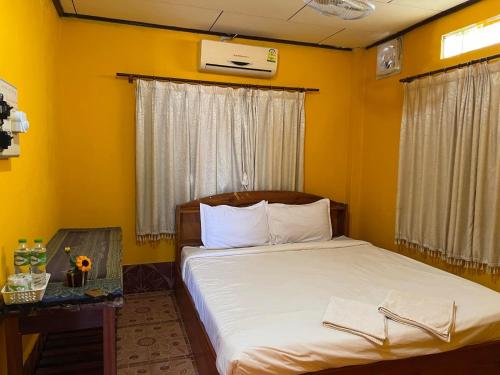 Muang KhôngにあるMR Mo Guest Houseの黄色の壁のベッドルーム1室