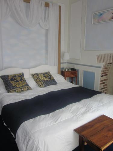 a white bed with two pillows on top of it at HOTEL LA COGNETTE A 25 Kilomètres de Châteauroux et 30 Kilomètres de Bourges in Issoudun