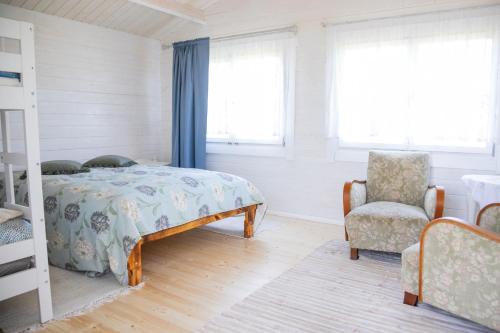 a bedroom with a bed and a chair and windows at Ohessaare mereäärne camping in Ohessaare