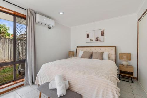 a white bedroom with a bed and a window at Affordable 1Bed Studio Close to Malls and Transit in Brisbane