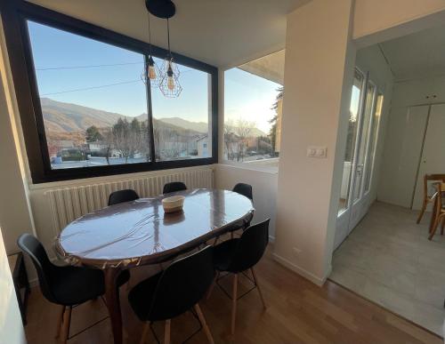 une table et des chaises dans une pièce avec une grande fenêtre dans l'établissement Appartement cosy dans une maison de caractère, à Tallard
