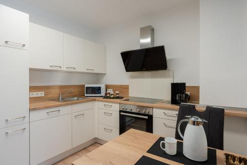 クレフにあるFerienweingut Jürgen Beth Parterreの白いキャビネットと花瓶付きのテーブルが備わるキッチン