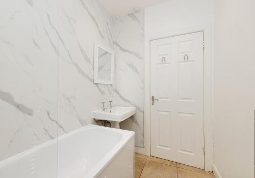 Baño blanco con bañera blanca y lavamanos en Grassmarket Apartments, en Edimburgo
