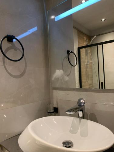 a bathroom with a white sink and a mirror at The City Landing Apartments At The Diamond in City in Accra