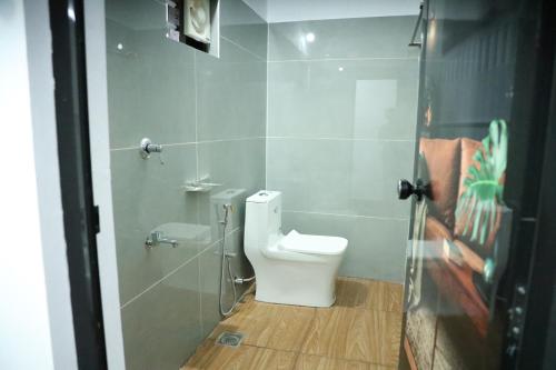 a bathroom with a white toilet and a shower at Bougainvillea Homestay in Nedukandam