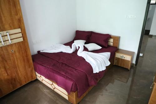 a bed with purple sheets and white towels on it at Bougainvillea Homestay in Nedukandam