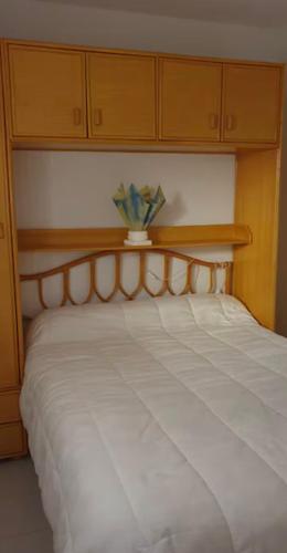 une chambre avec un lit blanc avec une tête de lit en bois dans l'établissement 300 metres de la mer, à Six-Fours-les-Plages