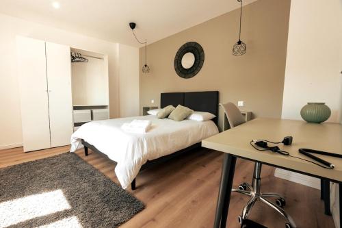 a bedroom with a bed and a desk and a table at La SUITE'HOME Super Bright Modern Apartment in Mulhouse