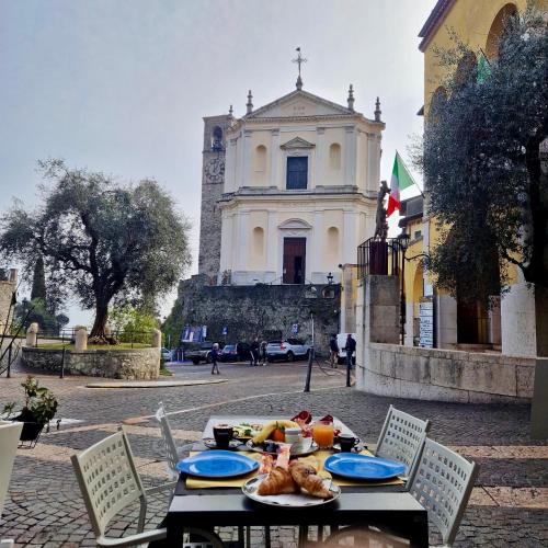Una mesa con comida frente a una iglesia. en B&B al Vittoriale da Maja, en Gardone Riviera