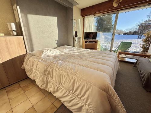 une chambre avec un grand lit et une grande fenêtre dans l'établissement Studio ski-in/ski-out à Notre-Dame-de-Bellecombe, piscine, tennis, parking - 4 personnes - FR-1-595-3, à Notre-Dame-de-Bellecombe