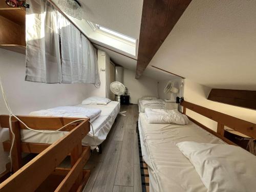 Cette chambre comprend 3 lits, une fenêtre et un plafond. dans l'établissement Jolie Maison de vacances, séjour climatisé, famille de 5 personnes, résidence MAS DE LA PLAGE 1, LRMP75, à Portiragnes