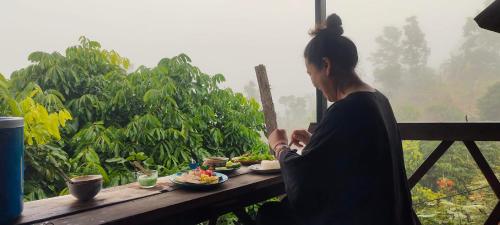 una mujer sentada en una mesa con un tazón de comida en Baan 2 Dao Farmstay, en Chiang Dao