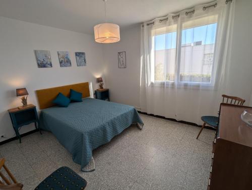 une chambre avec un lit avec des oreillers bleus et une fenêtre dans l'établissement Sol-y-Days Altitude Zéro en première ligne face à la plage, au Grau-du-Roi