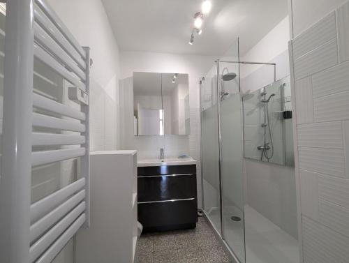 une salle de bain blanche avec un lavabo et une douche dans l'établissement Sol-y-Days Altitude Zéro en première ligne face à la plage, au Grau-du-Roi