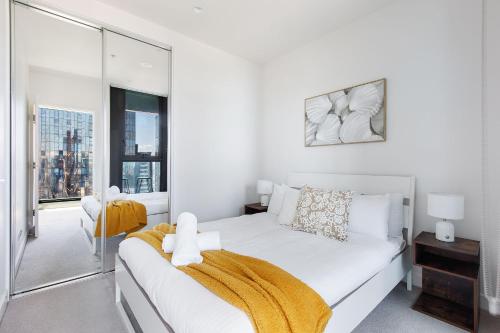 a white bedroom with a bed and a large window at Stunning Top Floor City Views 2BR Gem, Central CBD in Melbourne