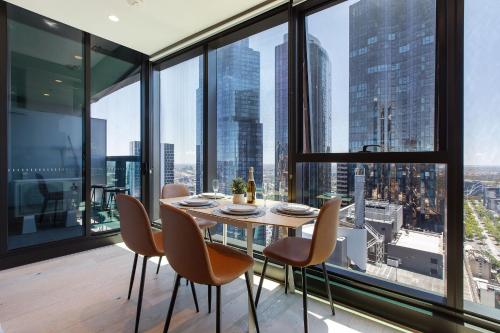 a dining room with a table and chairs and large windows at Stunning Top Floor City Views 2BR Gem, Central CBD in Melbourne