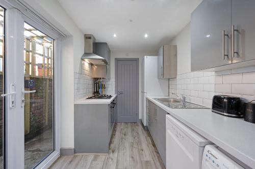 a kitchen with white cabinets and a counter top at Burnand House - Air Host & Stay - Sleeps 9 in Liverpool