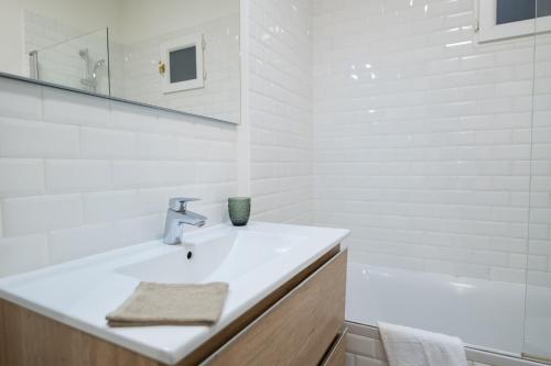 La salle de bains blanche est pourvue d'un lavabo et d'une baignoire. dans l'établissement Le Mandallaz - Coeur d 'Annecy, à Annecy