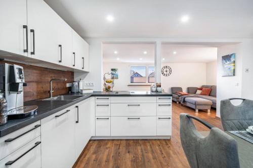 a kitchen with white cabinets and a living room at Schorsch's Ferienhaus in Winzeln