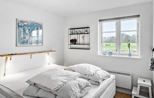 a white bedroom with a bed and two windows at Cozy Home In Nysted With Sauna in Nysted