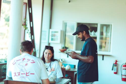 um homem a olhar para o telemóvel enquanto duas pessoas estão a trabalhar em Ella Soul Resort em Ella