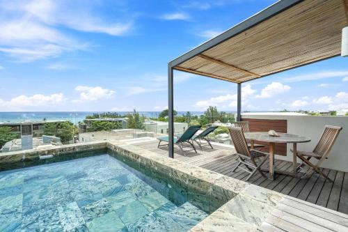 a pool on the roof of a house with a table and chairs at Aloah Penthouse - Seaview & Private Pool in Rivière Noire